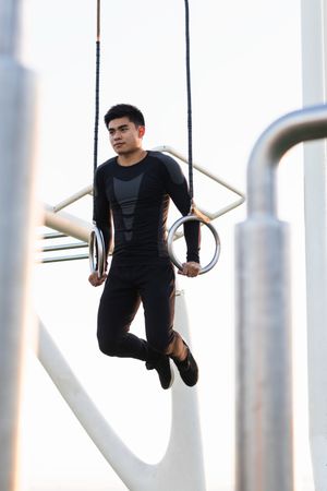 Athletic man practicing sport on gymnastic rings