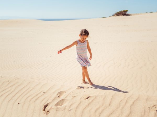 Cute little girl playing with sand at beach