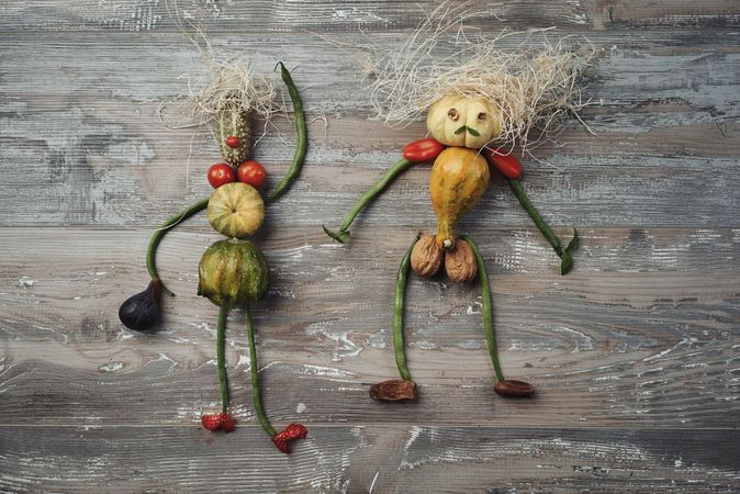 Flat lay of two figures made out of vegetables on wooden table