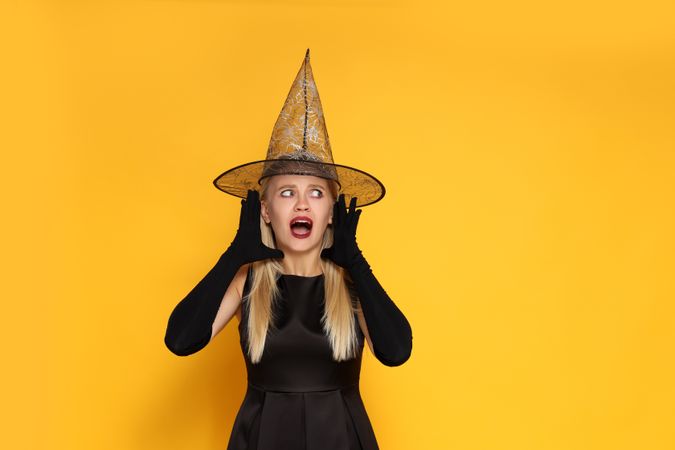 Concept of Halloween, young woman on yellow background