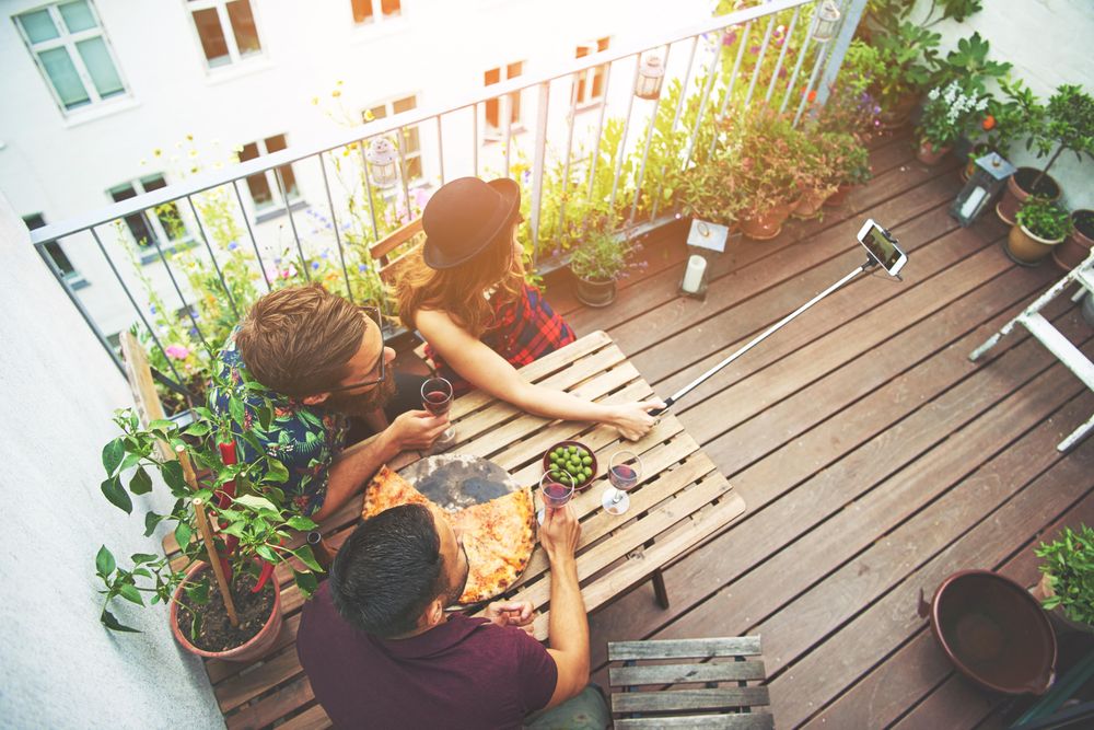 Top view of friends taking a selfie on table with pizza and wine