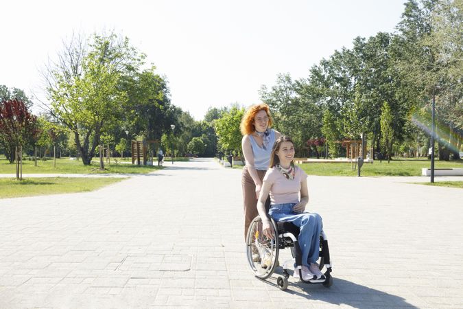 Woman pushing smiling friend in wheelchair