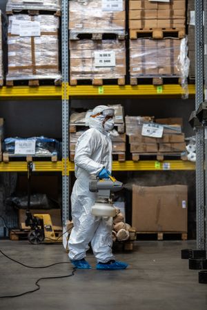Man in PPE holding sanitizing machine in warehouse during lockdown in Milano, Italy 