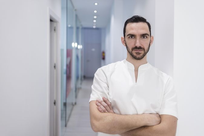 Portrait of a bearded doctor standing in the hospital hallway while looking camera