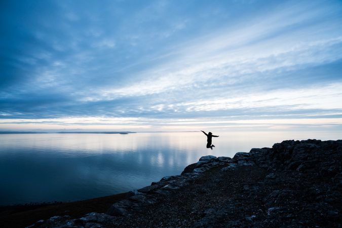 Happy man jumping on rocky coastline