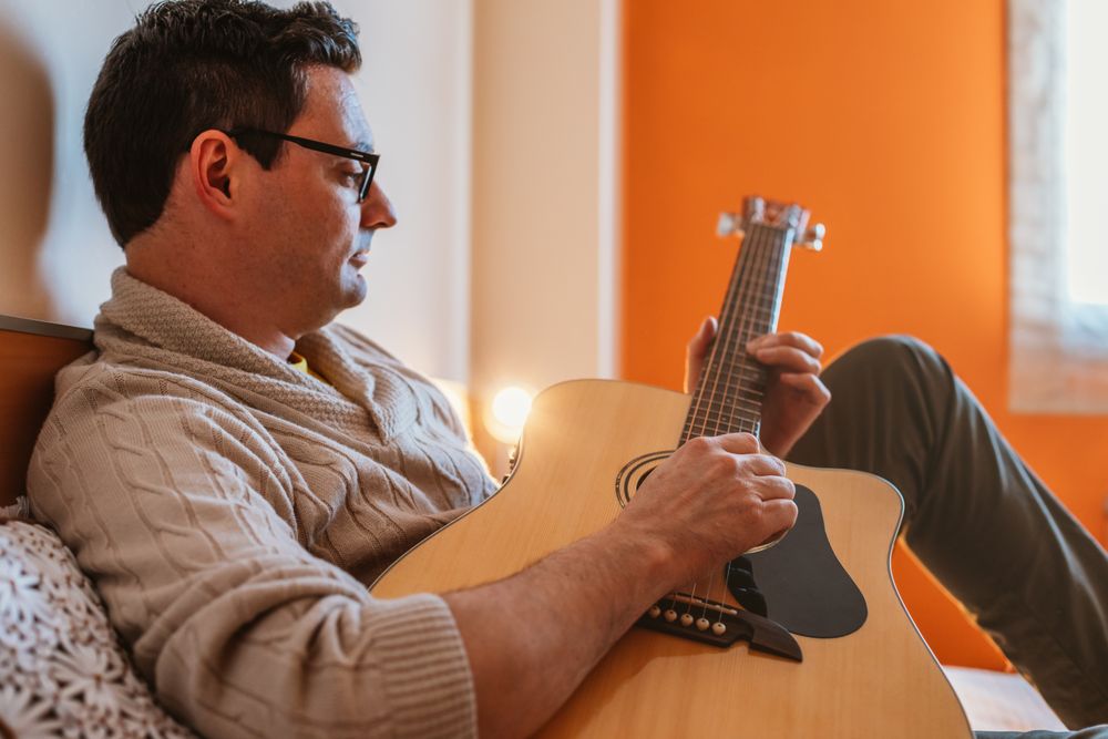 Man playing the guitar on the bed