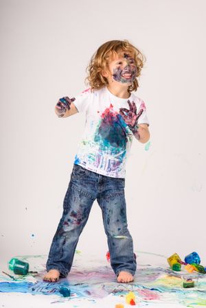 Delighted boy covered with paints in studio