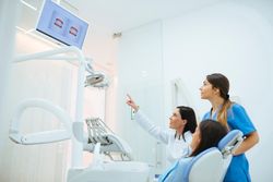 Dentist and assistant showing structure of teeth in picture to c