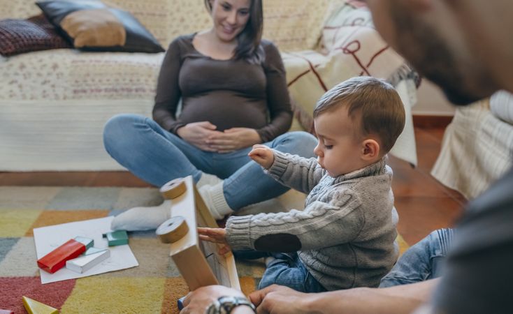 Father playing with toddler while the mother is looking at them