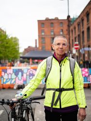 Older woman in neon wind breaker next to bicycle