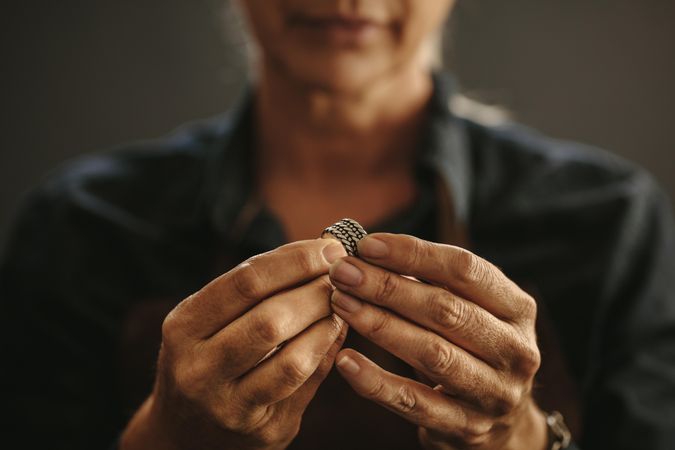 Close up of female jeweler hands examining ring at workshop