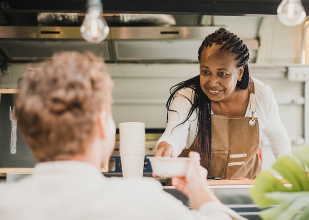 Chef woman serving take away order inside food truck