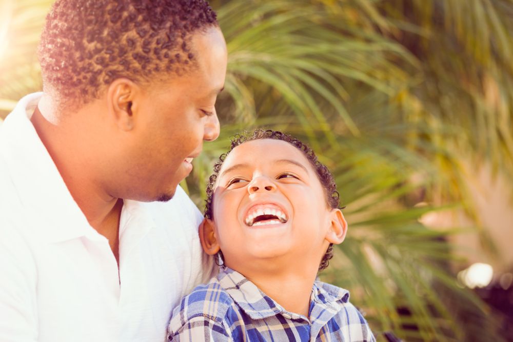 Black Father Laughing With Son Outdoors