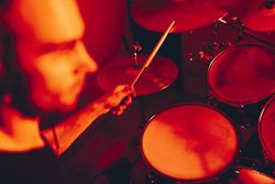 Man with drumsticks playing on drums in redness