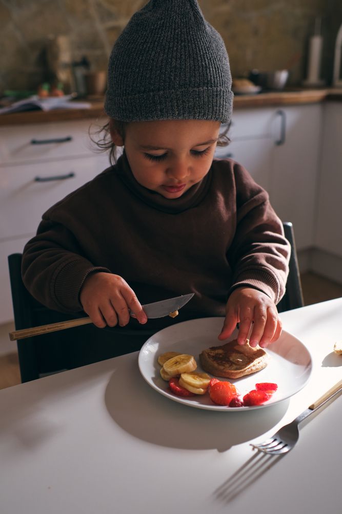 Little boy having breakfast with fruits and pancake