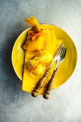 Top view of Easter table setting with yellow plate and Easter ornaments