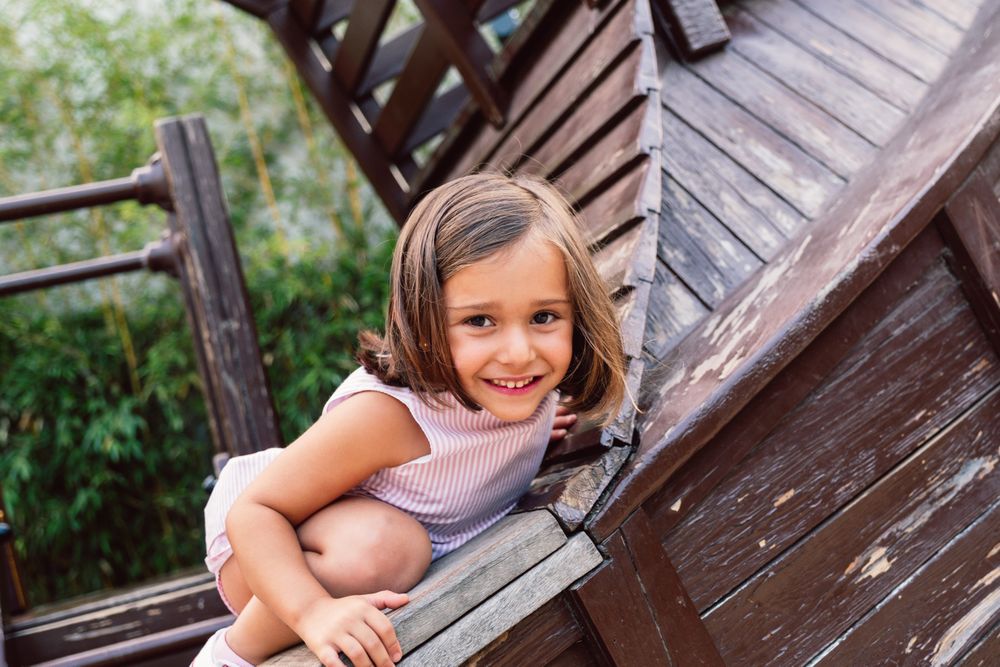 Smiling girl climbing onto wooden playground