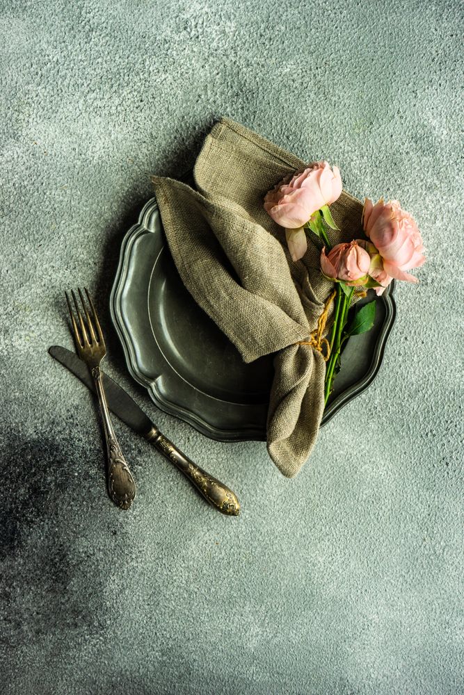 Top view of floral card with pink roses on dark table setting
