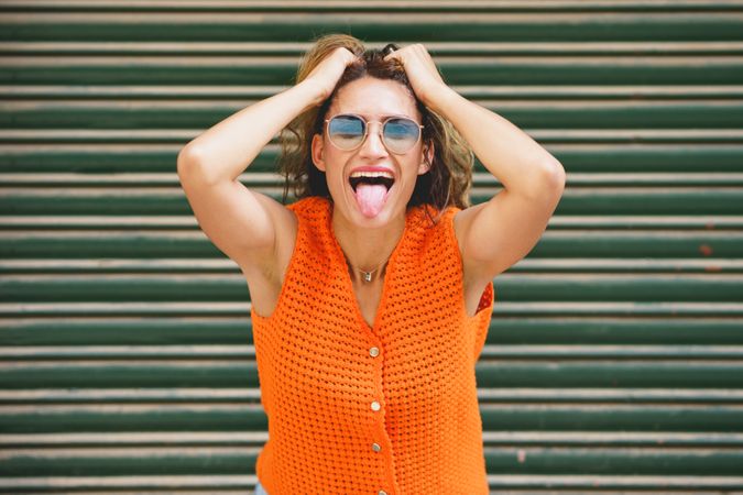 Woman holing her hair and sticking the tongue out smiling
