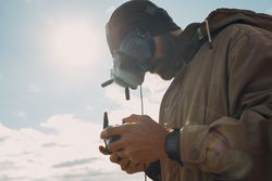 Adult man wearing goggles and holding a controller standing outdoor