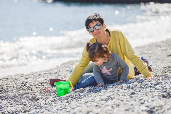 Woman and girl playing on a rocky beach