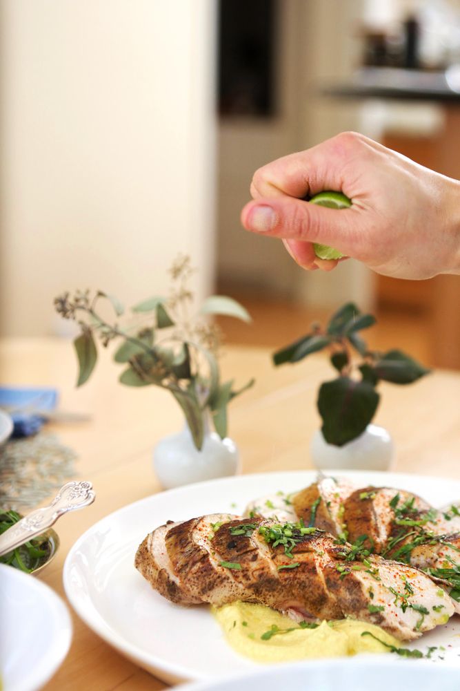 Cropped image of person squeezing lime over a dish of cooked meat