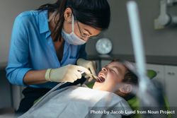 Female dentist examining teeth of little boy in dental clinic using dental tools 56Rxz5