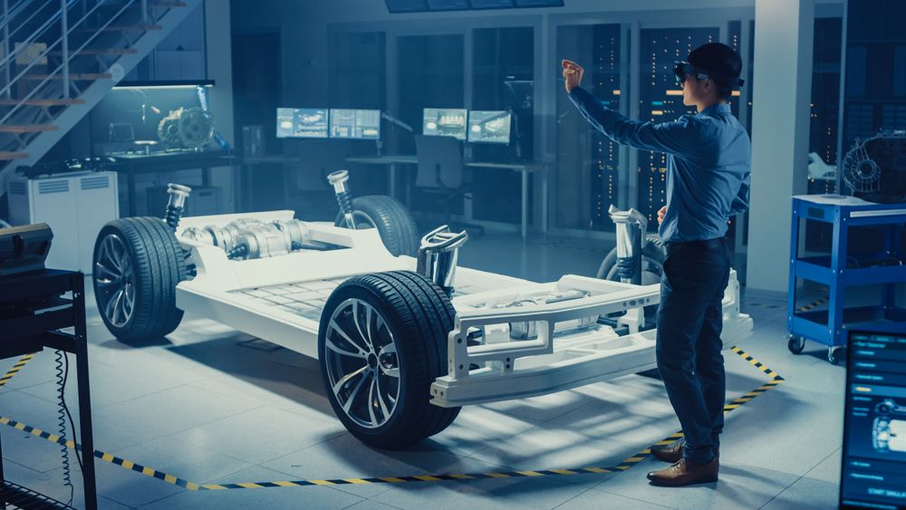 Automotive Engineer Working on Electric Car Chassis Platform, Using Augmented Reality Headset.