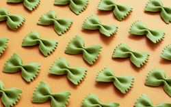 Green farfalle pasta on an orange table