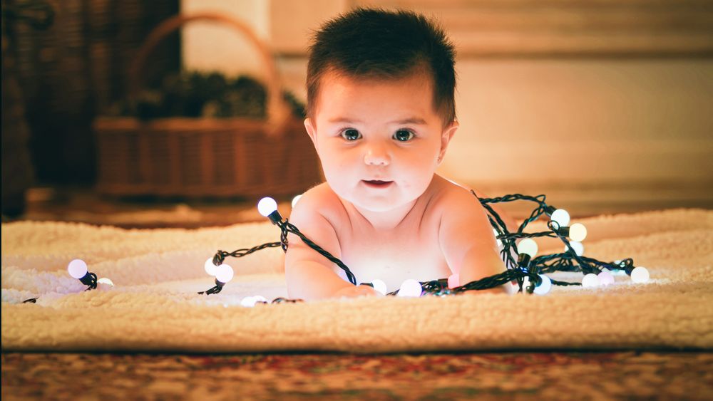 Baby playing with light garland on Christmas Day