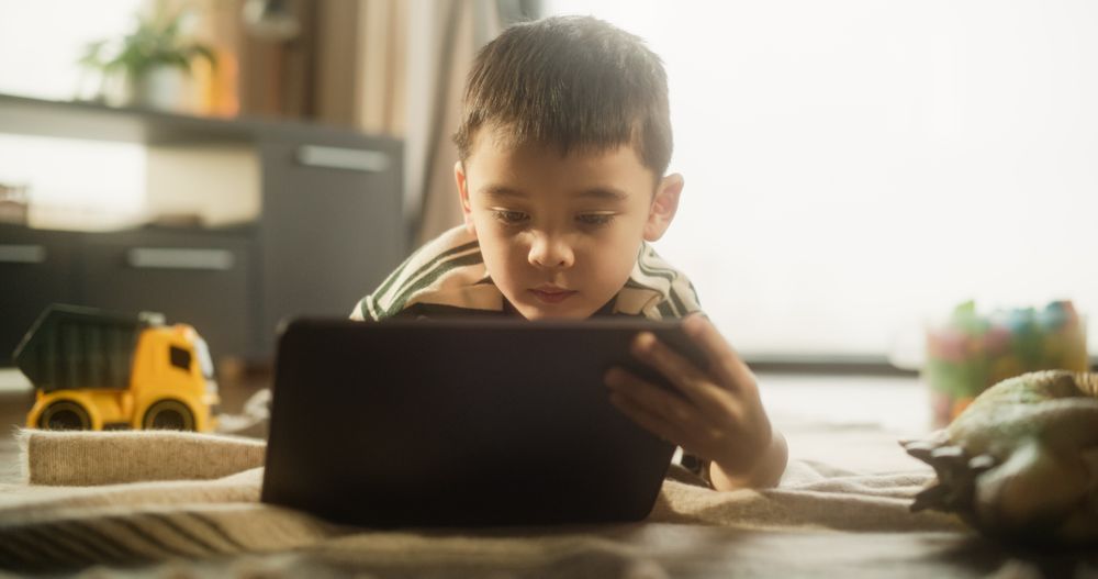 Portrait of an Asian Male Kid Using Digital Tablet in His Bright Stylish Room.