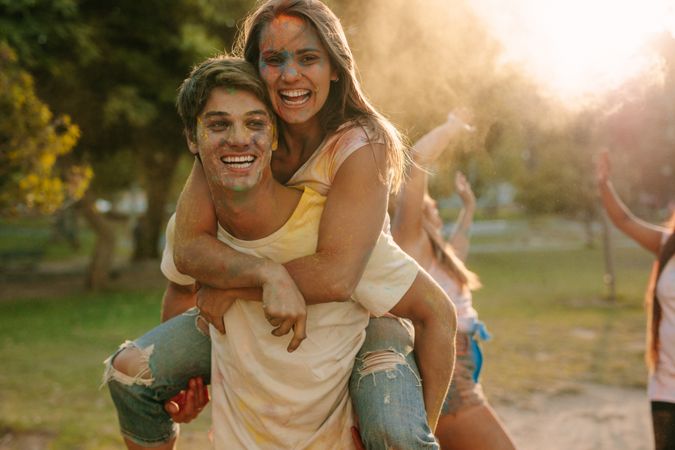 Man carrying his girlfriend on his back while playing holi.