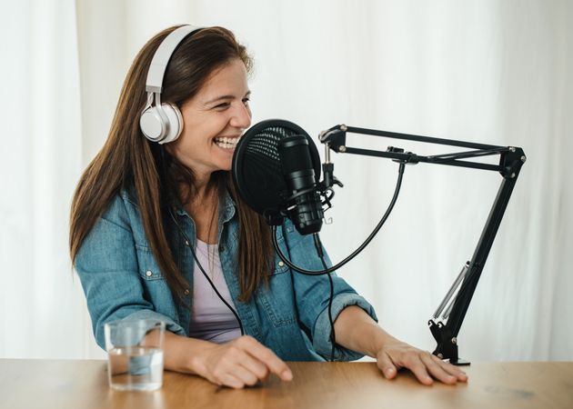 Happy woman recording podcast and laughing