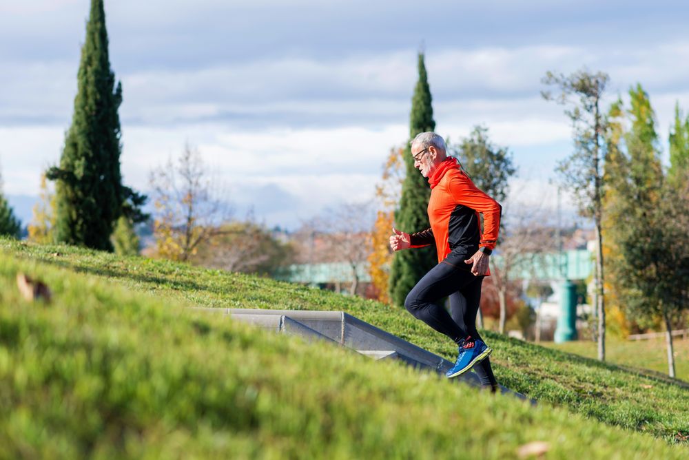 Older male jogging up stairs in park on fall day