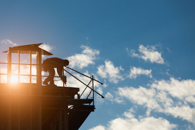 Construction Workers Silhouette on Roof of Building