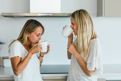 Women with coffee chatting in kitchen