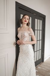 Magnificent pensive young bride in white lace dress looking at camera and pondering