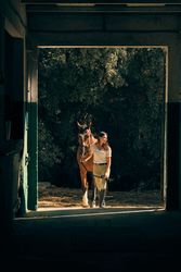 Horsewoman leading horse in barn