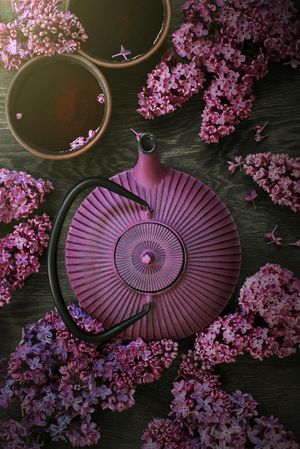 Top view of purple teapot with spring lilacs