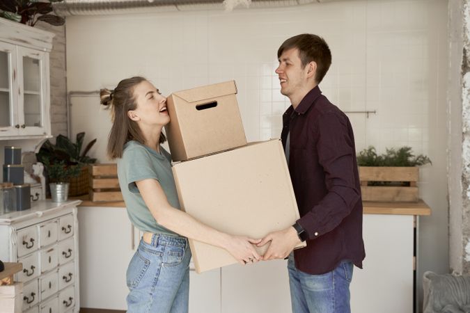 Young couple carrying big carton boxes in house