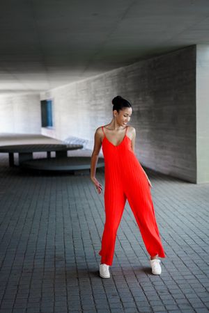 A Stylish Model Dressed in a Bright Red Jumpsuit Posing Gracefully in a Modern Architectural Space