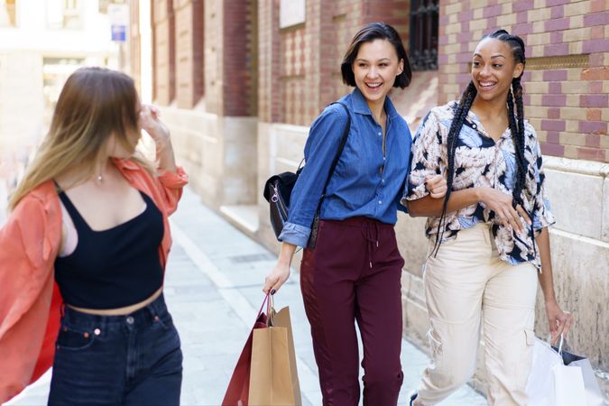 Women talking together while walking down street with shopping bags