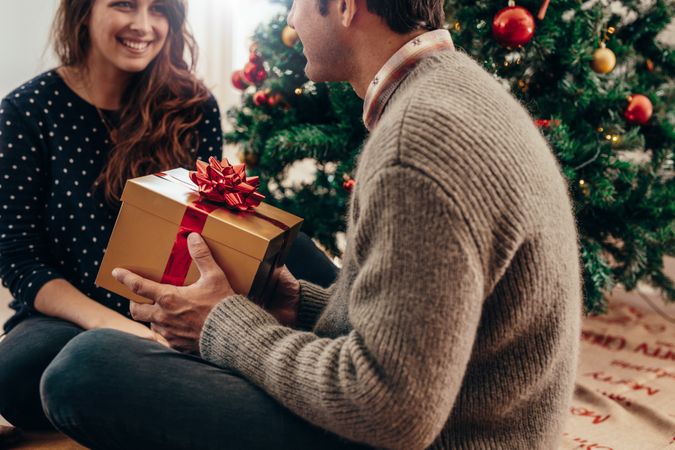 Man and woman exchanging Christmas gifts in their living room