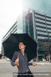 Businesswoman on city street with umbrella 4BRkE4