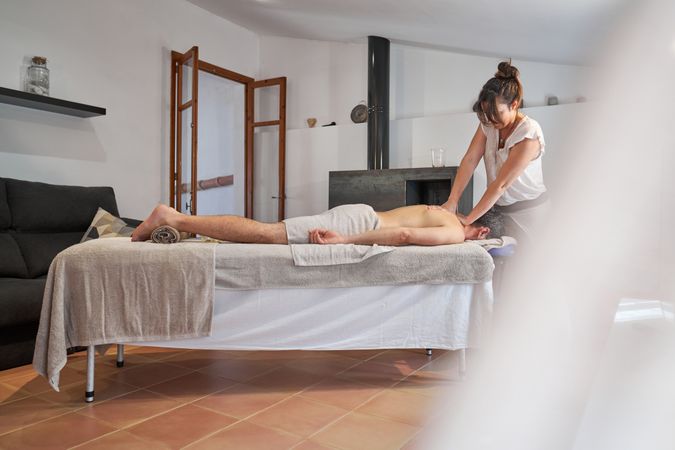 Masseuse doing neck massage to male customer