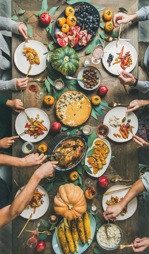 Group of people serving turkey over festive dishes, vertical composition