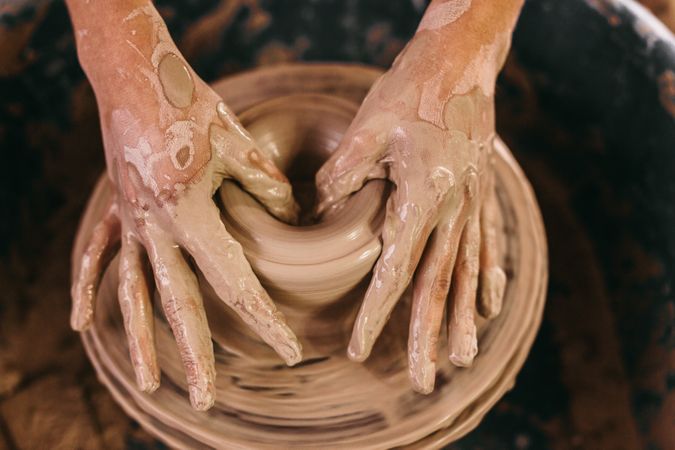 Potter moulding clay on pottery wheel into pot