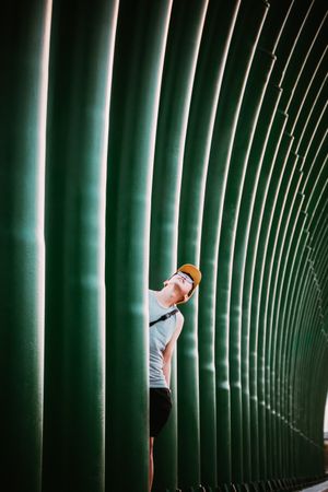 Man in yellow hat standing amid green pillars