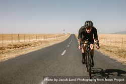 Athlete taking a bicycle ride on empty road 5zra8j