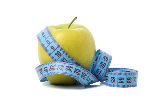 Measuring tape with apple isolated on light background